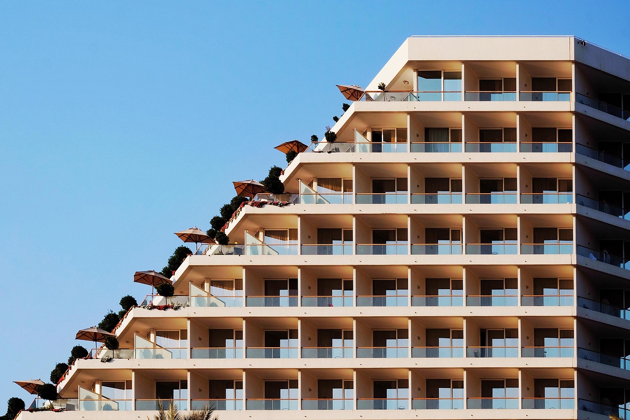 Edificio de condominios frente a la playa con balcones escalonados bajo un cielo despejado